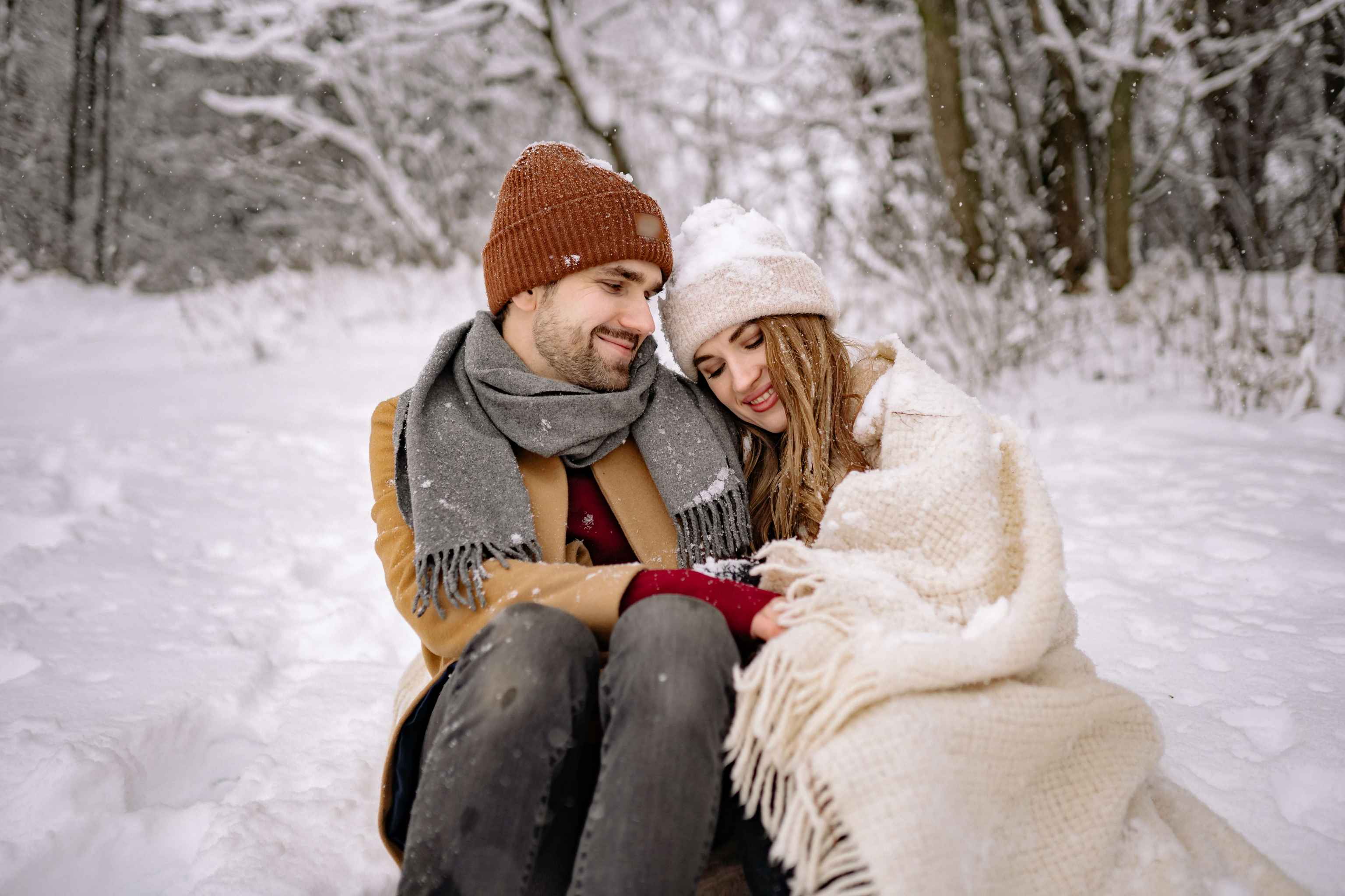 A man and a Cougar woman are sitting in the snow on a date.
